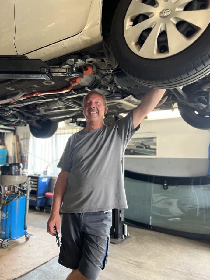 Kfz-Meister Dirk Menzel unter einem Auto auf der Hebebühne seiner Werkstatt